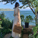 2025 Seaside niche design sense hollow waist hanging neck suspender dress women's summer waist thin fringed long skirt